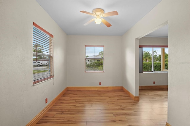 spare room with ceiling fan, light wood finished floors, and baseboards