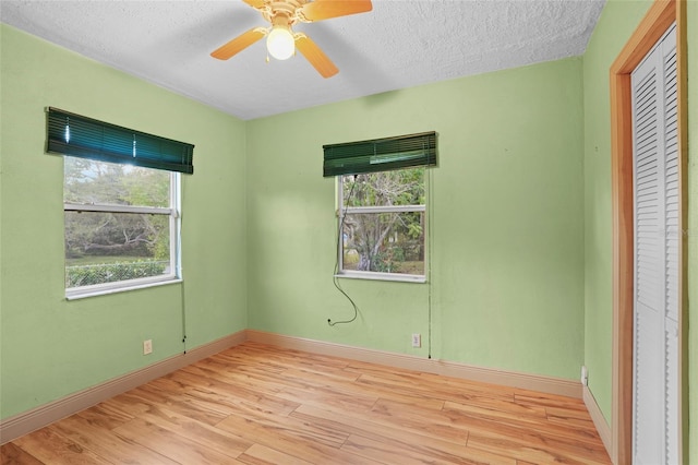 interior space featuring a ceiling fan, light wood-type flooring, a textured ceiling, and baseboards