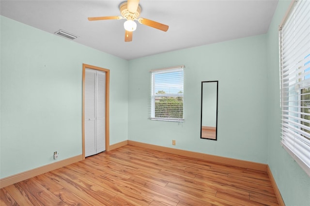 spare room featuring light wood-style floors, visible vents, baseboards, and a ceiling fan