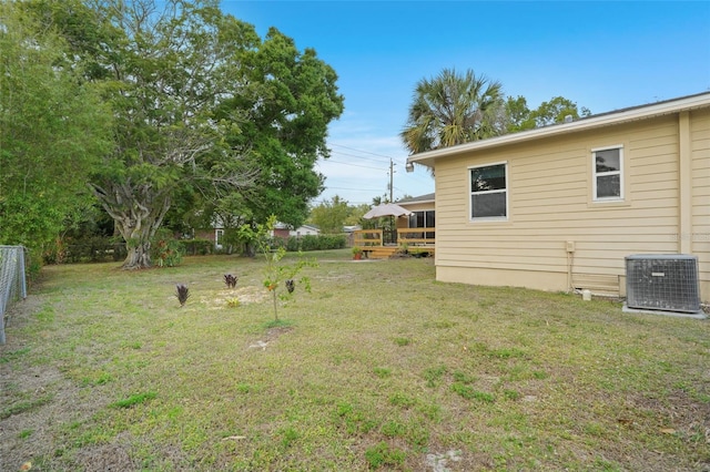 view of yard with central AC, fence, and a deck