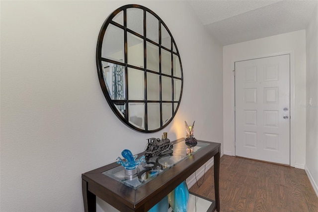 interior space featuring dark wood-style flooring, a textured ceiling, and baseboards