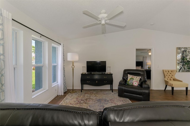 living room with a ceiling fan, vaulted ceiling, a textured ceiling, wood finished floors, and baseboards