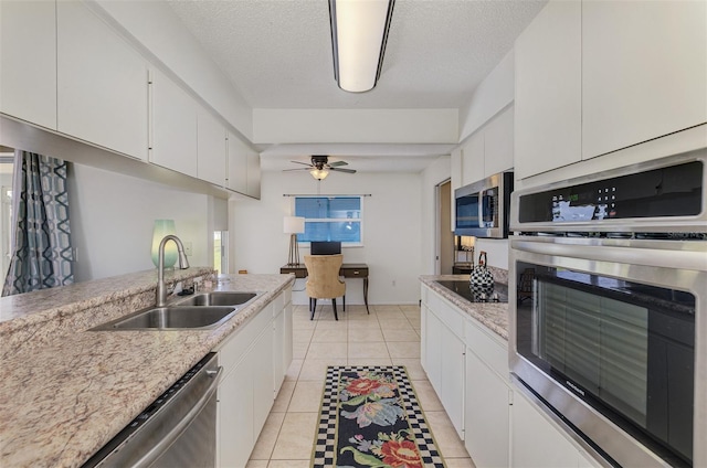 kitchen featuring light tile patterned floors, ceiling fan, a sink, white cabinetry, and appliances with stainless steel finishes