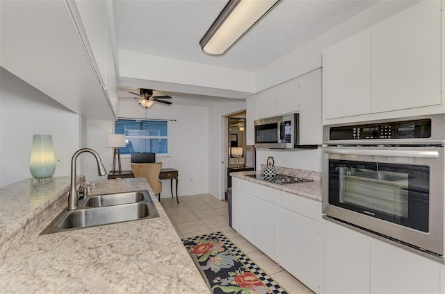 kitchen with light tile patterned floors, stainless steel appliances, light countertops, white cabinetry, and a sink