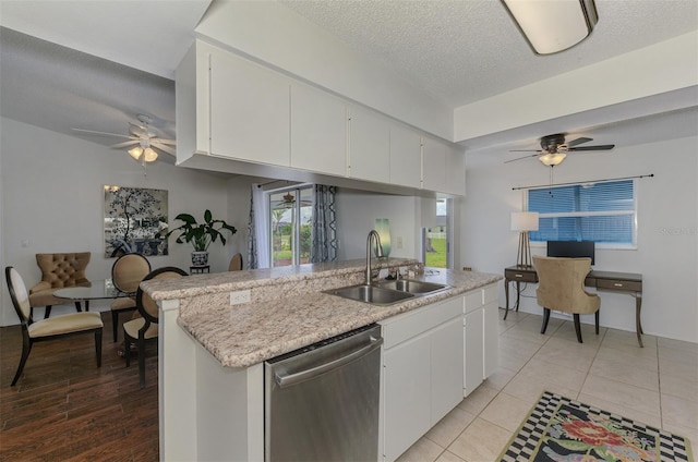 kitchen with a sink, white cabinetry, light countertops, and stainless steel dishwasher