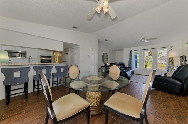 dining room with lofted ceiling, ceiling fan, visible vents, and wood finished floors