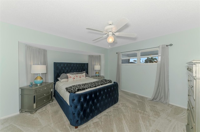 bedroom featuring light colored carpet, ceiling fan, a textured ceiling, and baseboards