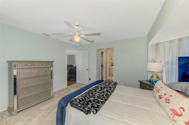 bedroom featuring visible vents, ensuite bathroom, a ceiling fan, light carpet, and a textured ceiling