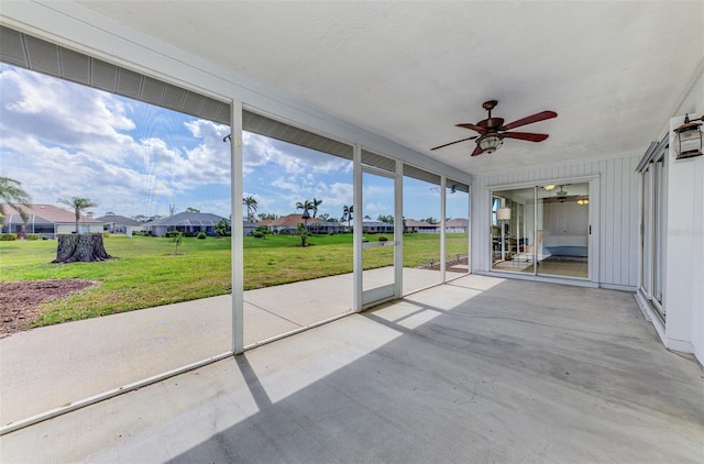 unfurnished sunroom with ceiling fan and a residential view