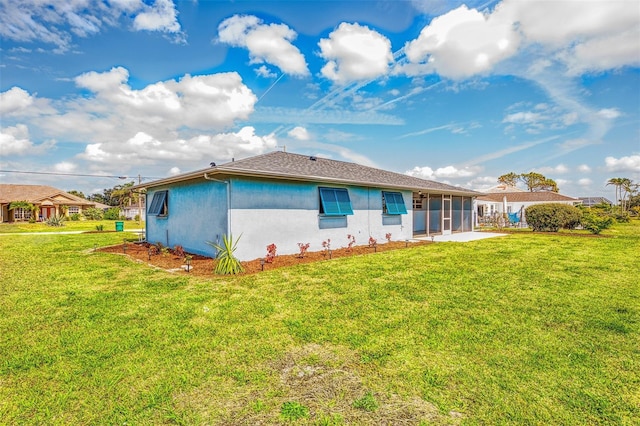 rear view of house with a yard and stucco siding