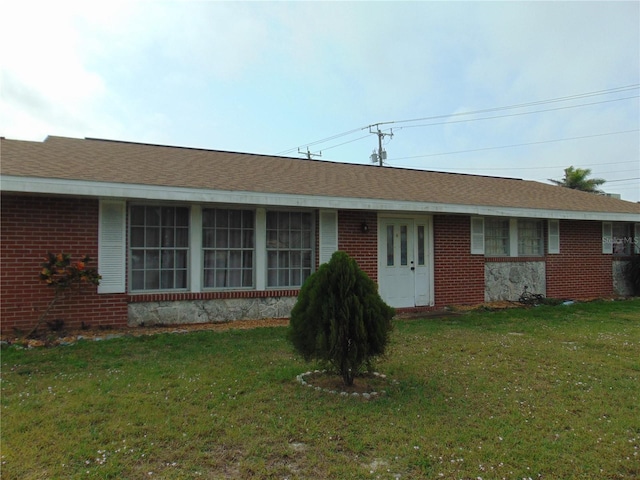 ranch-style home with brick siding, a front lawn, and a shingled roof