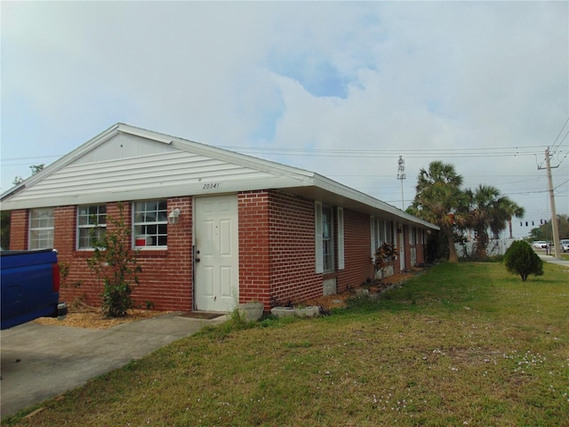 view of side of home with brick siding and a yard