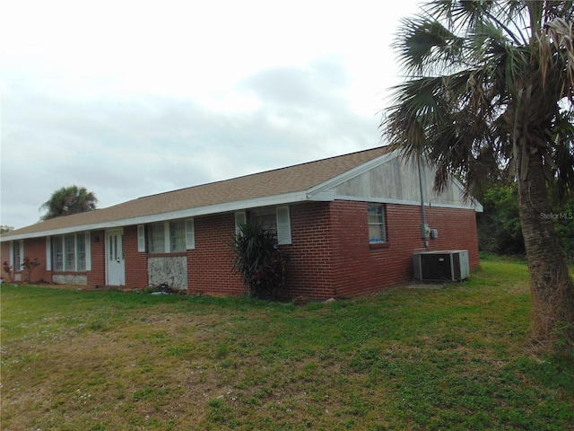 view of front of house featuring central AC unit, a front yard, and brick siding