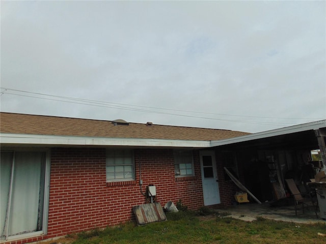 view of home's exterior with roof with shingles and brick siding