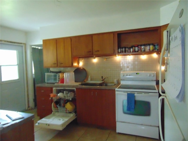 kitchen featuring light tile patterned floors, white appliances, a sink, tasteful backsplash, and brown cabinetry