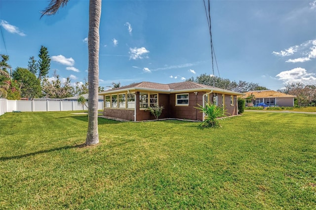 rear view of property with a lawn and fence