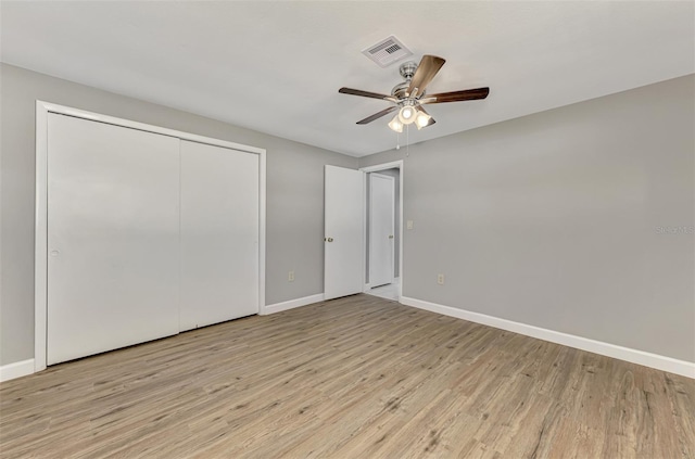 unfurnished bedroom with wood finished floors, a ceiling fan, visible vents, baseboards, and a closet