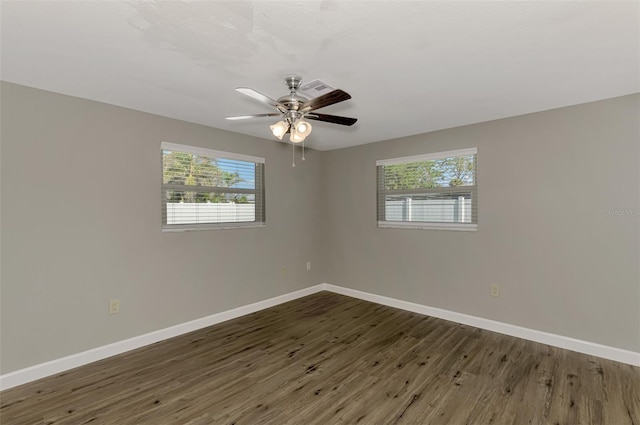 empty room featuring a wealth of natural light, ceiling fan, baseboards, and wood finished floors