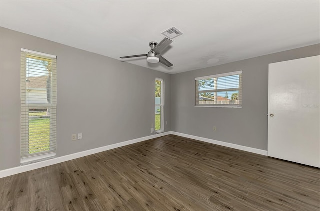 unfurnished room featuring dark wood-style floors, baseboards, visible vents, and a wealth of natural light