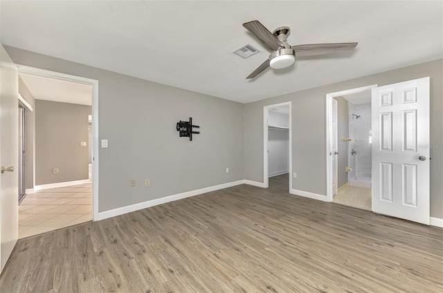 unfurnished bedroom featuring baseboards, visible vents, light wood finished floors, and ensuite bathroom