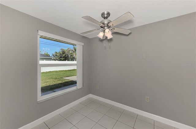 spare room featuring light tile patterned flooring, a ceiling fan, and baseboards