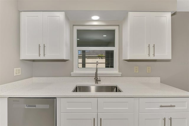 kitchen with a sink, light stone countertops, white cabinets, and stainless steel dishwasher