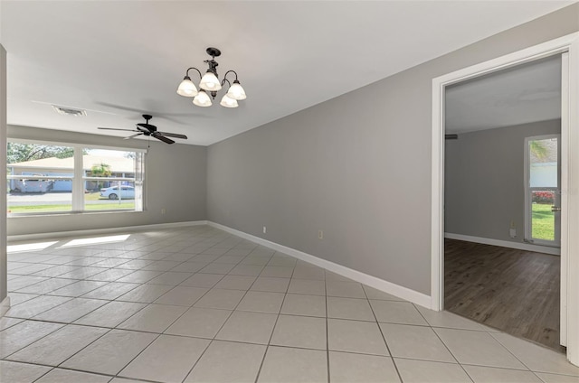 empty room featuring light tile patterned flooring, visible vents, and baseboards