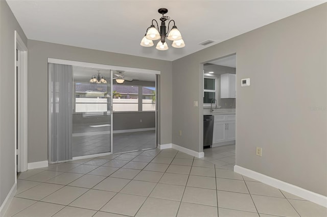 unfurnished dining area with a notable chandelier, visible vents, light tile patterned flooring, a sink, and baseboards