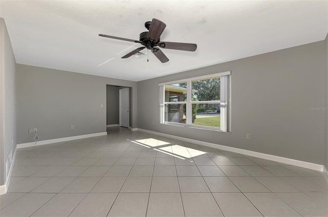 unfurnished room with light tile patterned floors, a ceiling fan, and baseboards