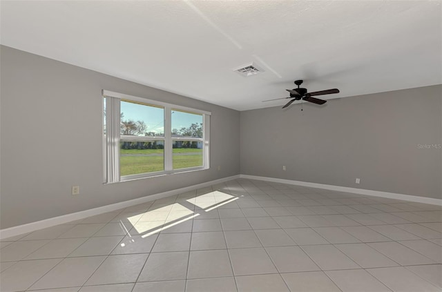 empty room with light tile patterned floors, baseboards, visible vents, and ceiling fan