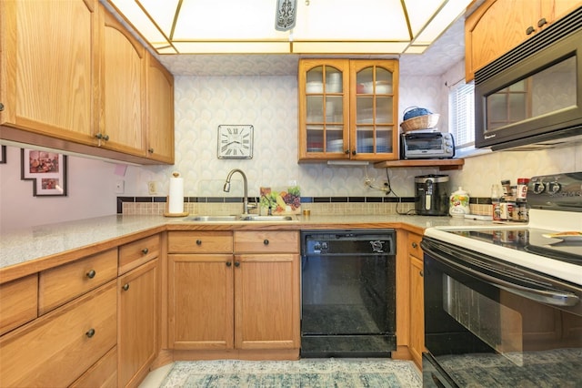 kitchen with a sink, glass insert cabinets, black appliances, and light countertops