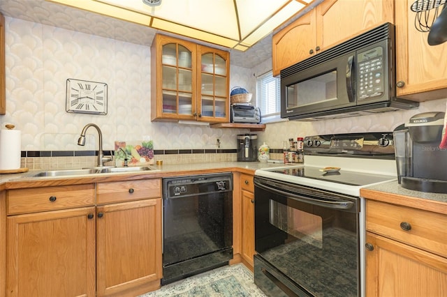 kitchen featuring wallpapered walls, glass insert cabinets, light countertops, black appliances, and a sink