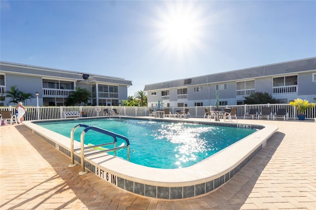 community pool with a patio area and fence