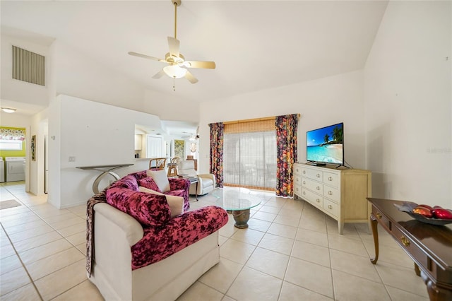 living room featuring light tile patterned floors, visible vents, a high ceiling, a ceiling fan, and independent washer and dryer