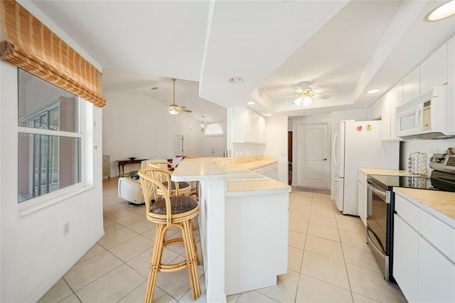 kitchen with a peninsula, white appliances, a breakfast bar area, and a ceiling fan