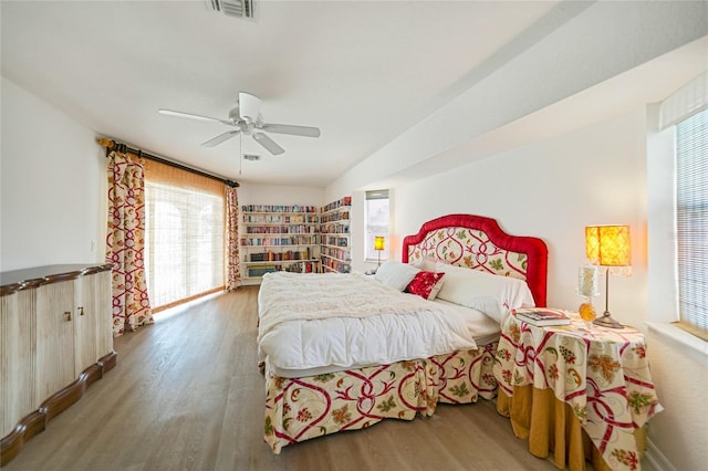 bedroom with ceiling fan, wood finished floors, and visible vents