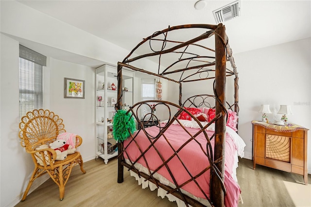 bedroom featuring visible vents, baseboards, and wood finished floors