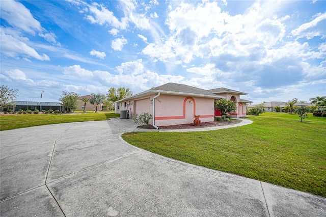 view of front of property with central air condition unit, stucco siding, a garage, driveway, and a front lawn