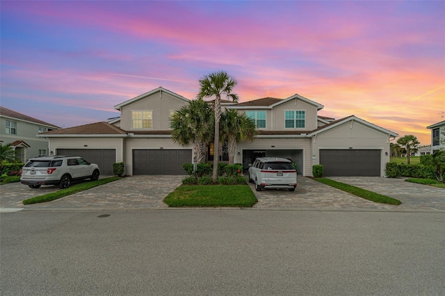 multi unit property with decorative driveway and an attached garage