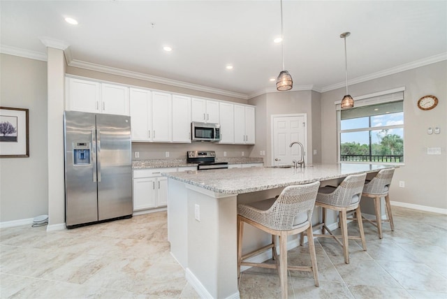 kitchen with an island with sink, ornamental molding, appliances with stainless steel finishes, white cabinets, and a sink