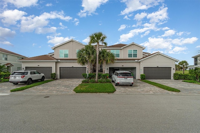 multi unit property with decorative driveway, an attached garage, and stucco siding