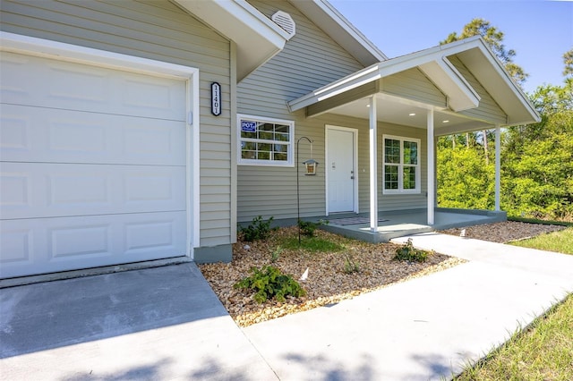 view of exterior entry with a garage and covered porch