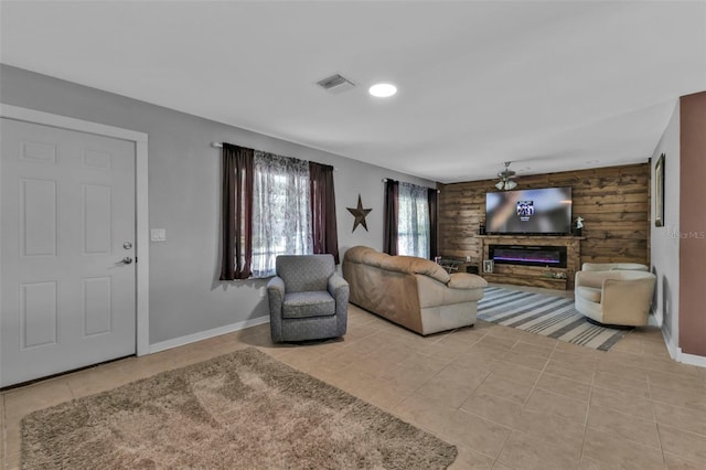 living area featuring baseboards, visible vents, a glass covered fireplace, and light tile patterned flooring