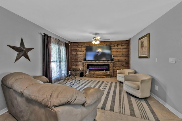 living area with a glass covered fireplace, ceiling fan, baseboards, and light tile patterned floors