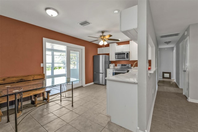 kitchen with stainless steel appliances, white cabinets, visible vents, and light tile patterned floors