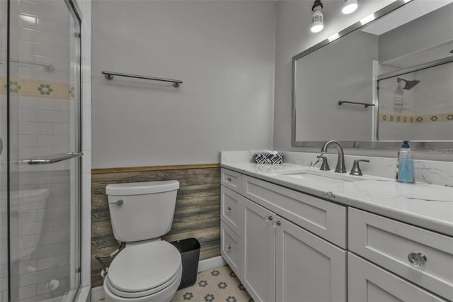 bathroom featuring a stall shower, wainscoting, vanity, and toilet