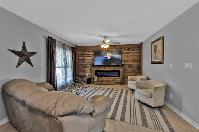 living area with a glass covered fireplace, baseboards, ceiling fan, and light tile patterned flooring