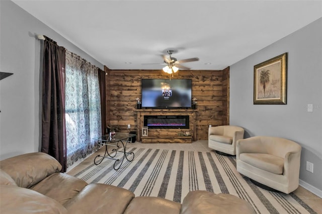 living room featuring ceiling fan, a glass covered fireplace, baseboards, and rustic walls