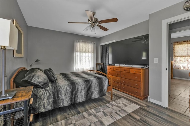 bedroom featuring baseboards, ceiling fan, multiple windows, and wood finished floors