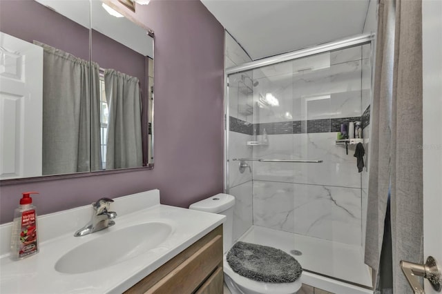 bathroom with vanity, a shower stall, and toilet